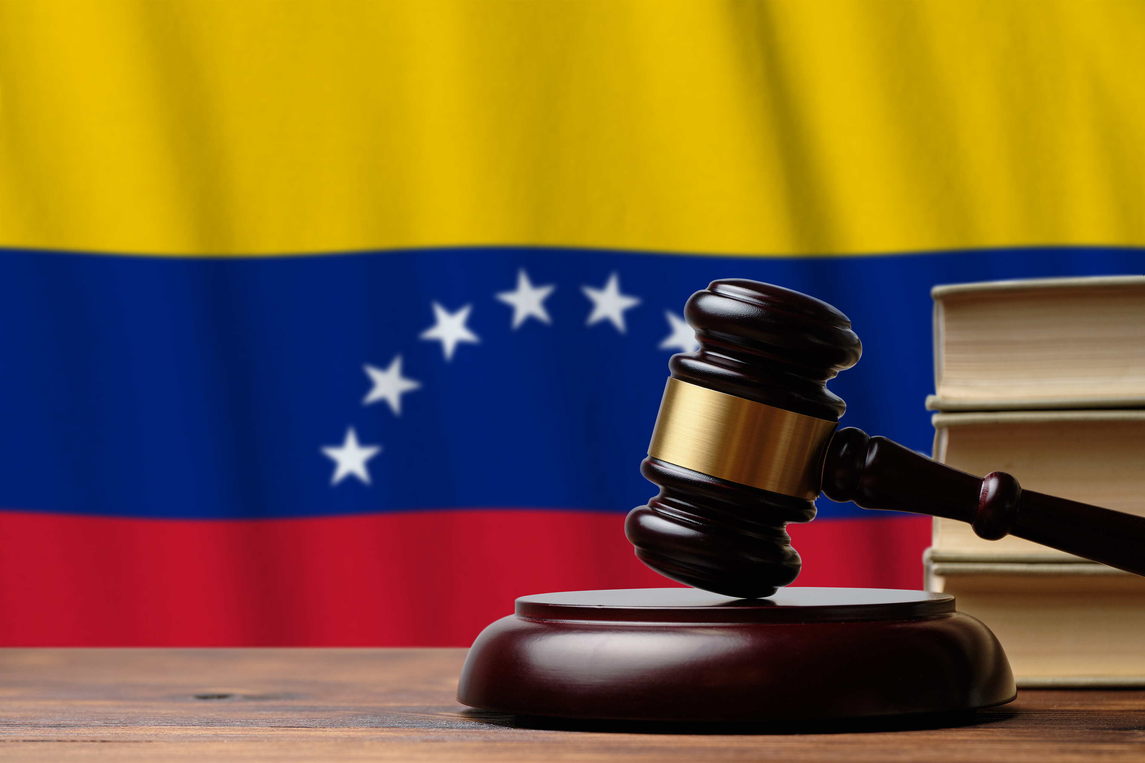 A imagem mostra a bandeira da Venezuela e um bastão de justiça.