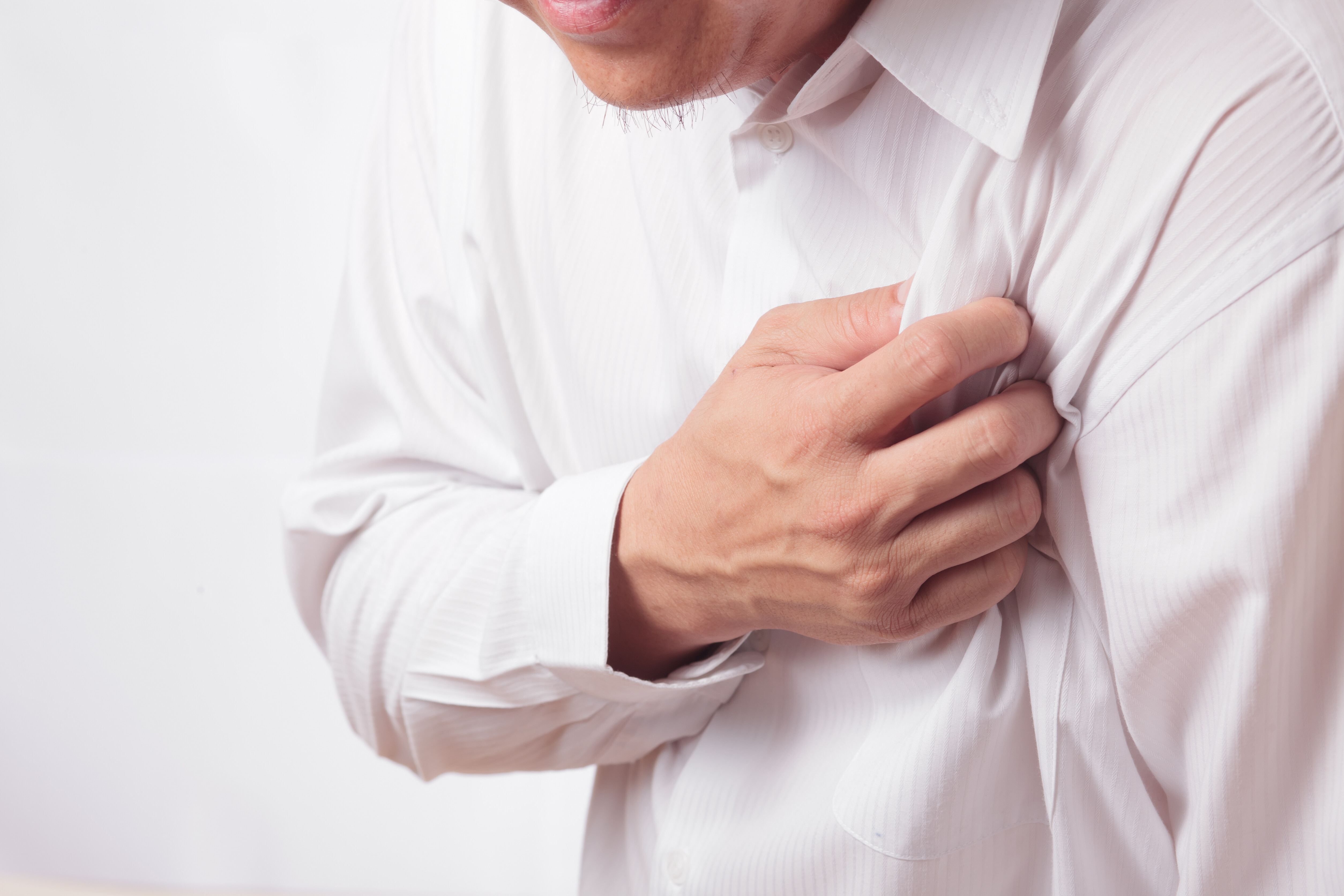 A imagem mostra um homem levando a mão ao peito após ter um infarto do miocárdio.