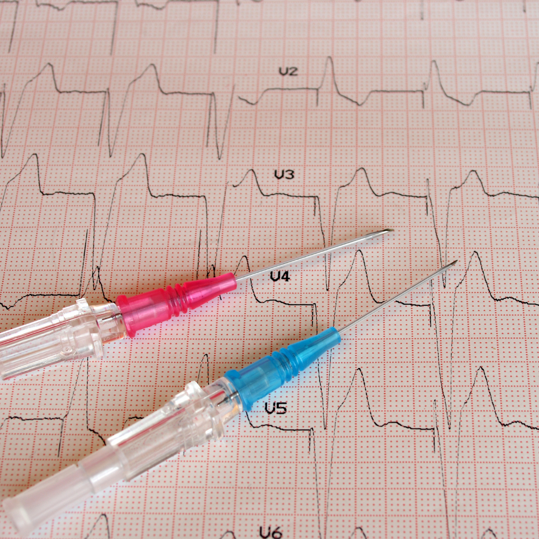 A imagem mostra duas seringas com agulhas e um eletrocardiograma.