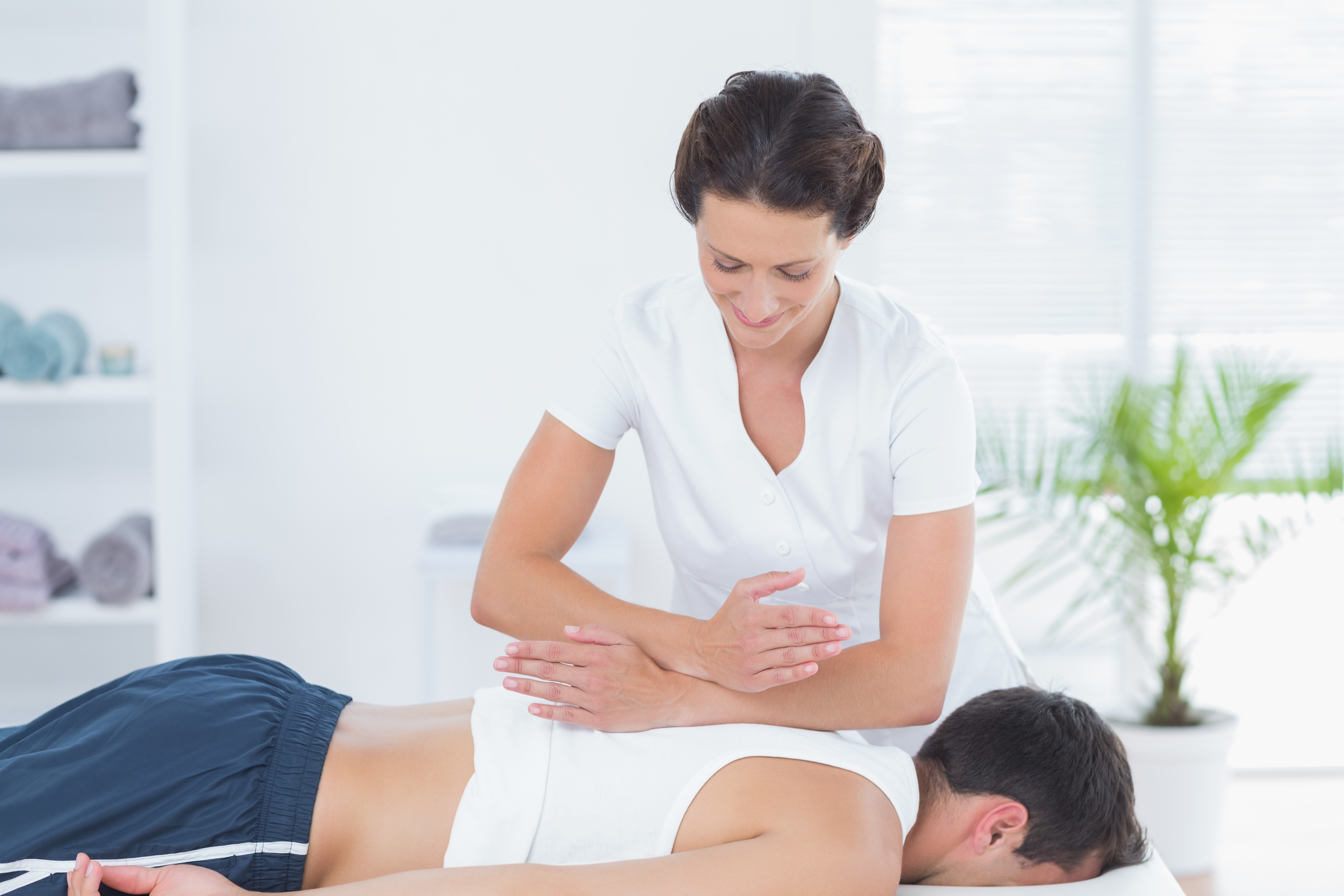 A imagem mostra uma fisioterapeuta fazendo massagem em um paciente.