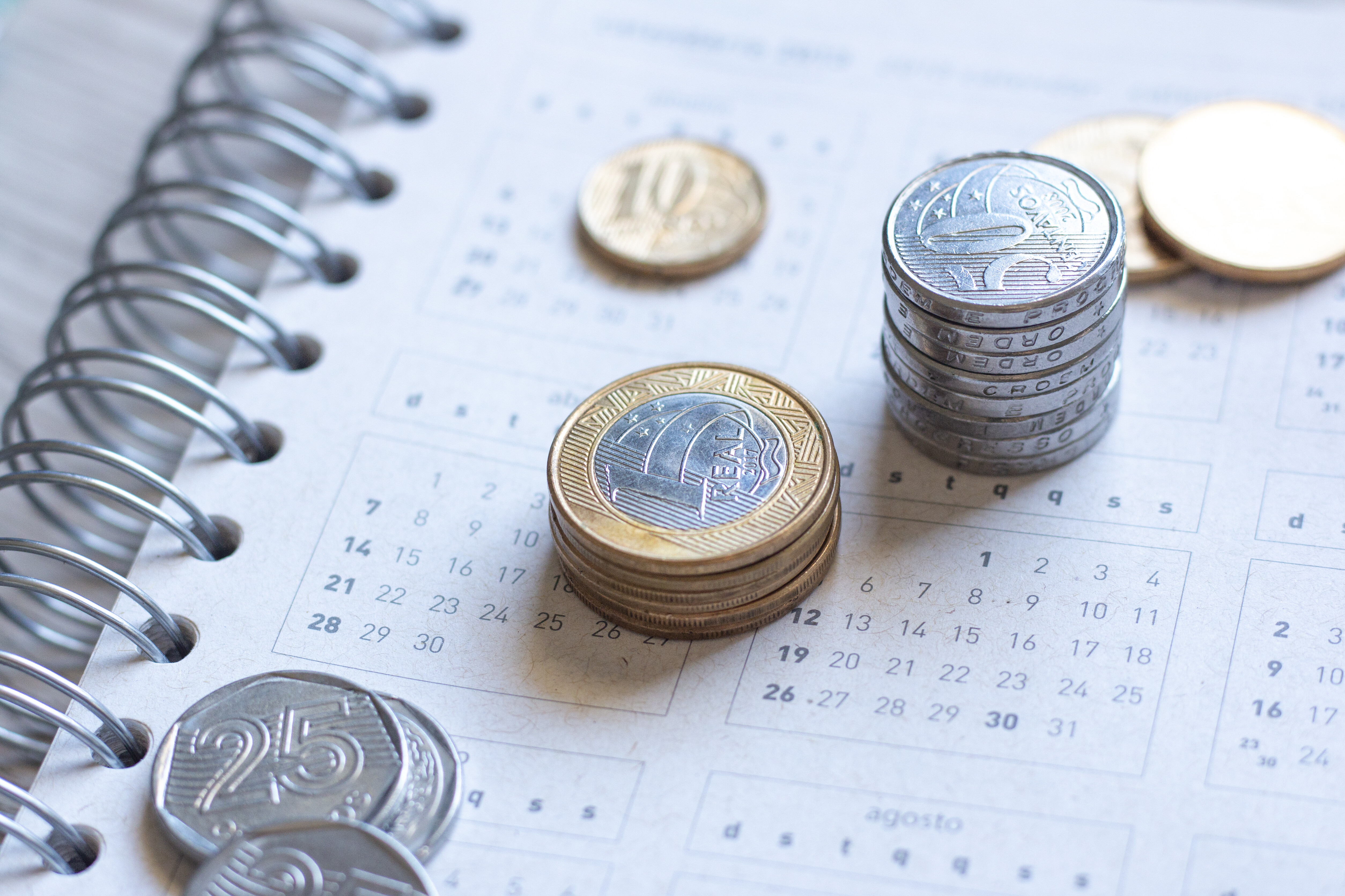 A imagem mostra várias moedas em cima de um caderno.