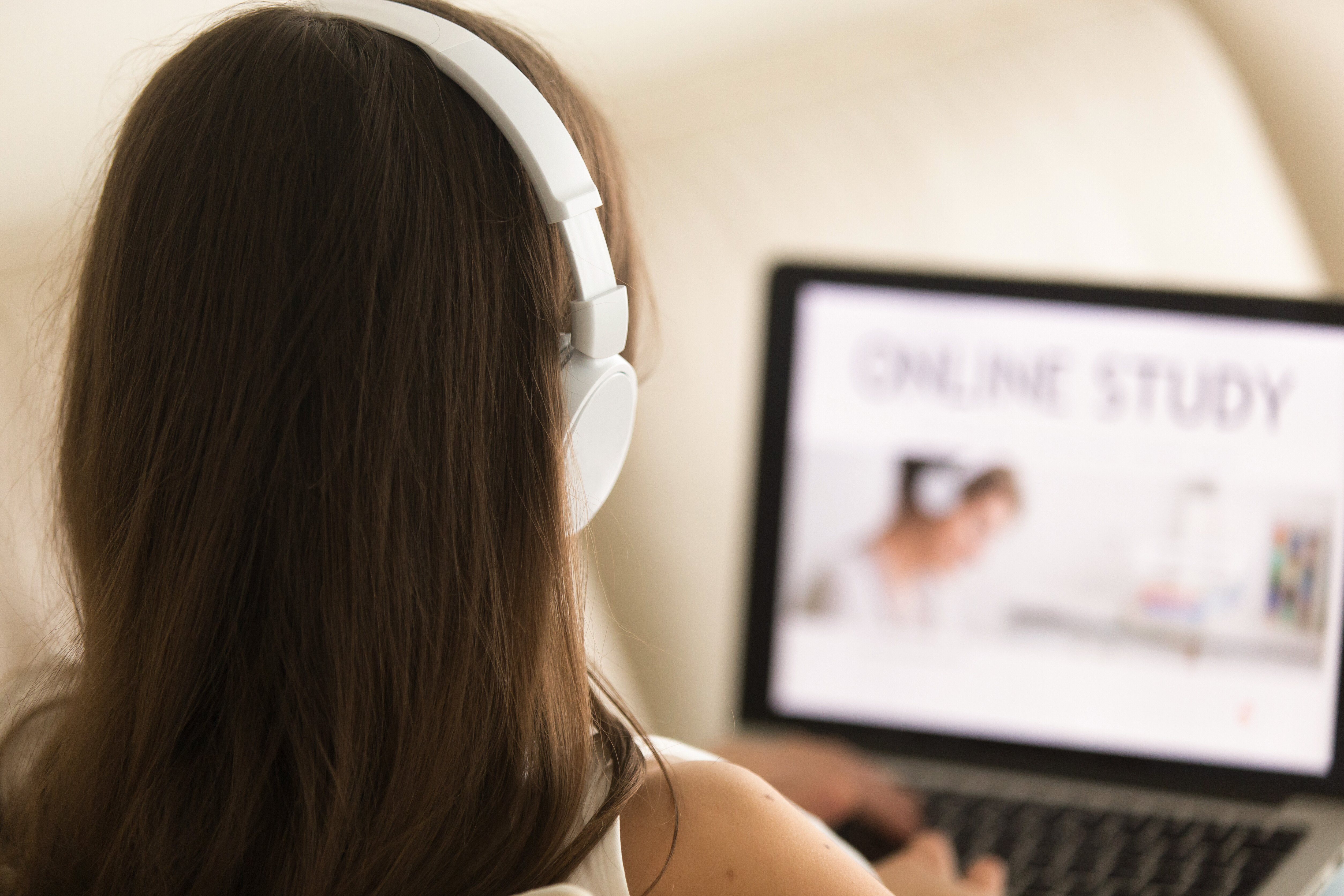 A imagem mostra uma mulher com fones de ouvido usando um computador.